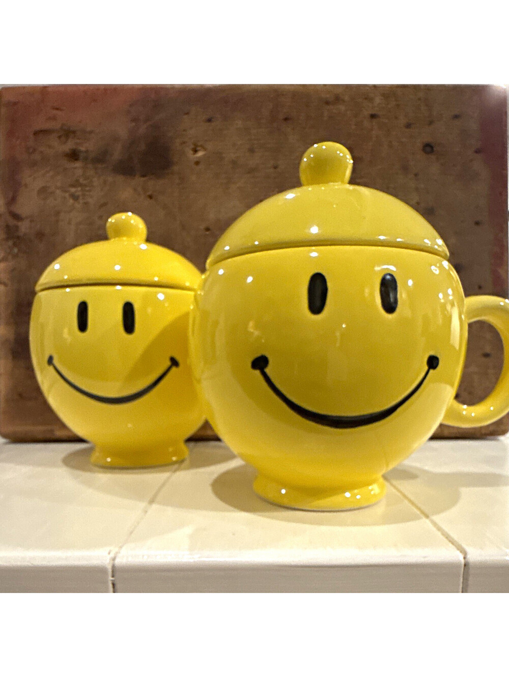 This is a set of vintage 1980s Teleflora yellow ceramic smiley face lidded mugs